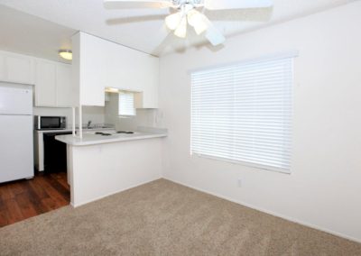 landmark gardens living area with ceiling fan, window and kitchen